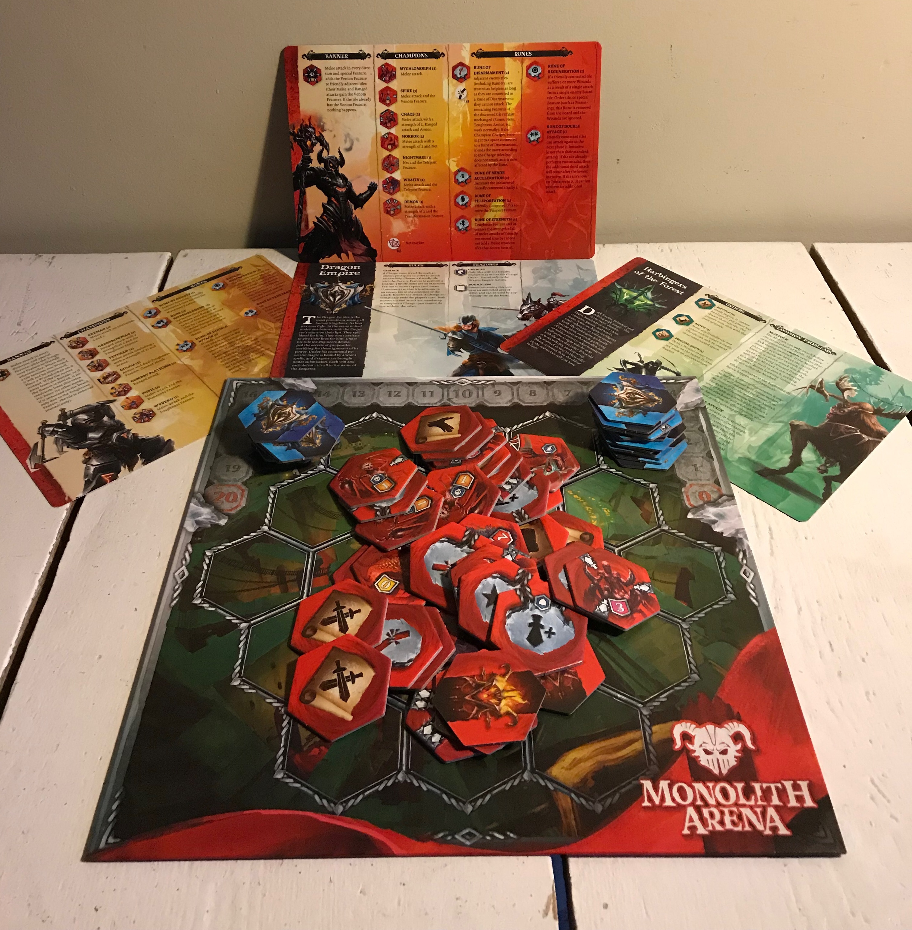 Overzicht van enkele componenten: het spelbord, de hulpmatten per factie en enkele tegels.